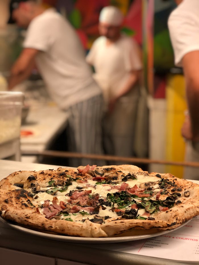 Delicious pizza topped with fresh ingredients in an Italian pizzeria kitchen setting.
